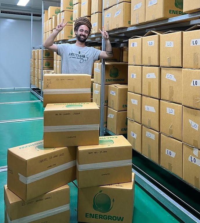 Team member celebrating beside stacked cartons of finished orders ready to leave the facility